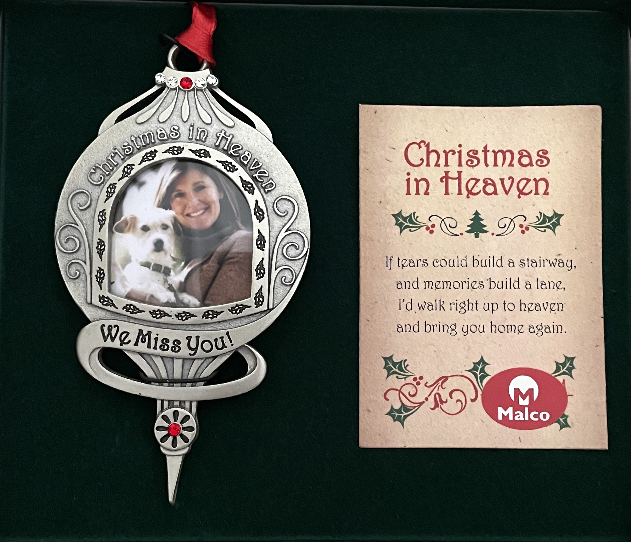 WE MISS YOU CHRISTMAS IN HEAVEN ORNAMENT. SILVER ENAMEL METAL ORNAMENT ADORNED WITH CRYSTAL AND SIAM STONES ON RED SATIN RIBBON. HOLDS 1.5 IN PHOTO 4.75X2.75. GIFT BOXED