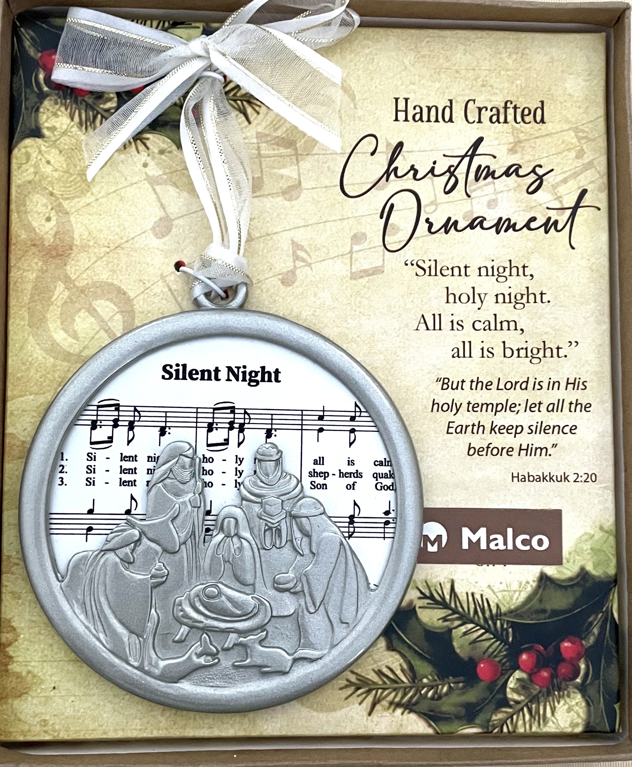 SILENT NIGHT CHRISTMAS CAROL ORNAMENT. CAST METAL, FINISHED IN SILVER ENAMEL, FRAME SUBLIMATED WOOD WHICH FEATURES SHEET MUSIC. HANGS FROM WHITE ORGANZA RIBBON. ORNAMENT SITS ON A DECORATIVE PAD, HIGHLIGHTING A SEFMENT OF THE CAROL WITH CORRESPONDING SCRIPTURE. 3.5 IN DIAMETER. WINDOW BOXED