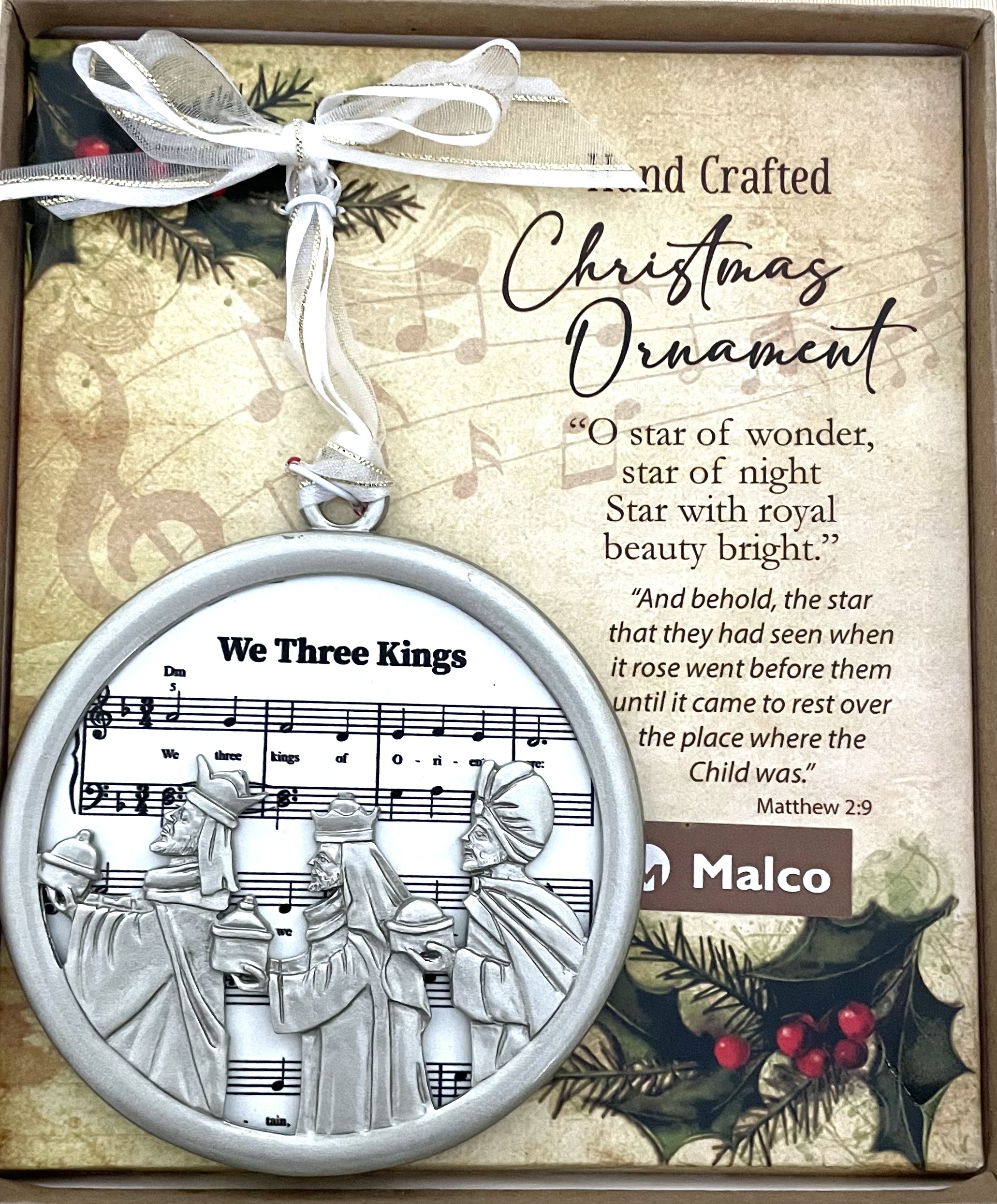 WE THREE KINGS CHRISTMAS CAROL ORNAMENT. CAST METAL, FINISHED IN SILVER ENAMEL, FRAME SUBLIMATED WOOD WHICH FEATURES SHEET MUSIC. HANGS FROM WHITE ORGANZA RIBBON. ORNAMENT SITS ON A DECORATIVE PAD, HIGHLIGHTING A SEFMENT OF THE CAROL WITH CORRESPONDING SCRIPTURE. 3.5 IN DIAMETER. WINDOW BOXED